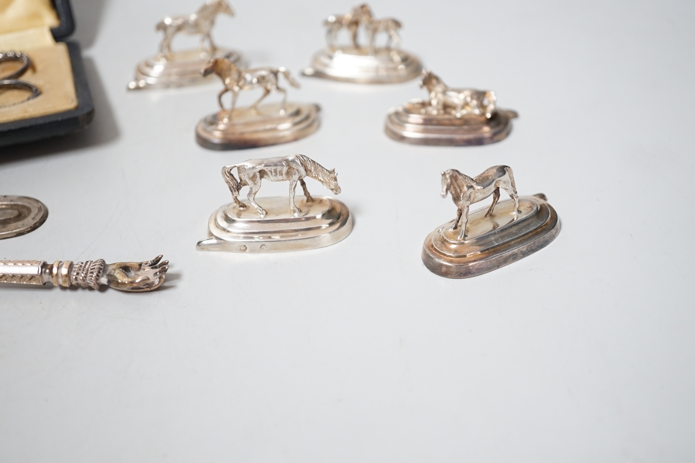 Six assorted Spanish white metal horse menu holders, 43mm, a cased necessaire set, a cigar cutter and a French white metal spoon with hand terminal.